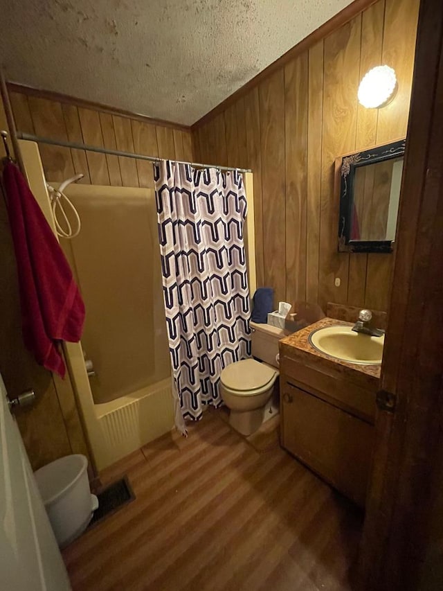 full bathroom with a textured ceiling, wood walls, hardwood / wood-style floors, shower / bath combo, and vanity