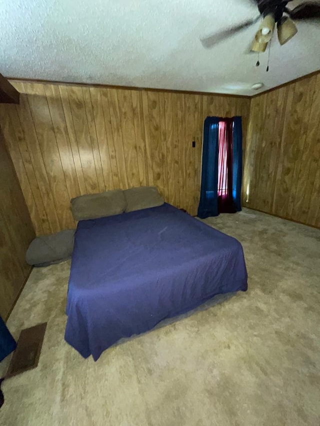 carpeted bedroom with ceiling fan, wooden walls, a textured ceiling, and pool table