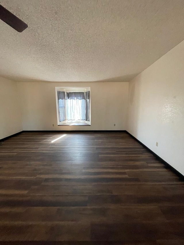 spare room with a textured ceiling and dark hardwood / wood-style floors