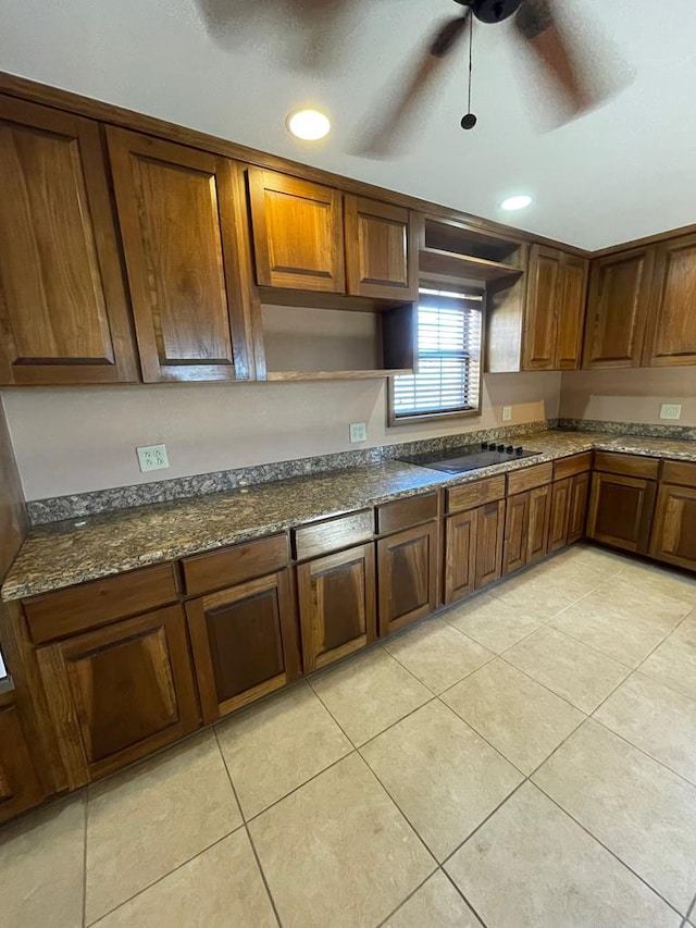 kitchen featuring dark stone counters, ceiling fan, light tile patterned flooring, and black electric cooktop