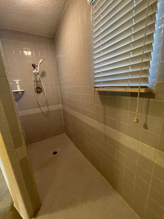 bathroom with a textured ceiling and tiled shower