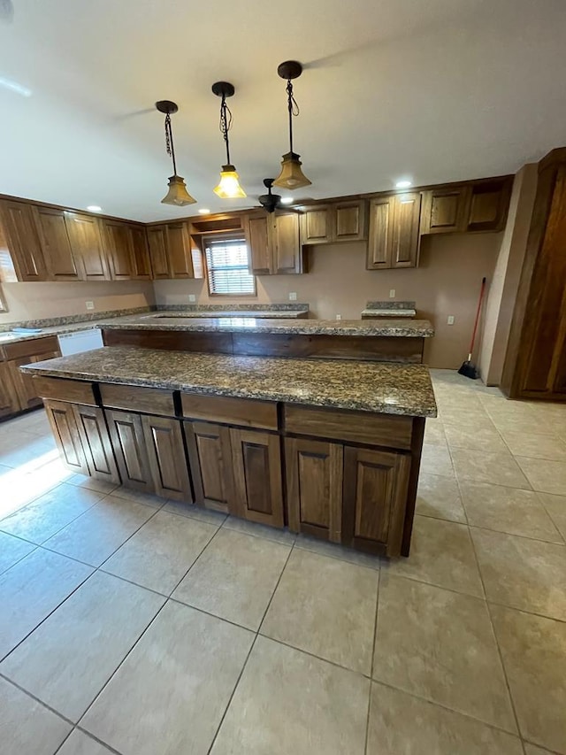 kitchen featuring a kitchen island, dark stone countertops, light tile patterned floors, and hanging light fixtures