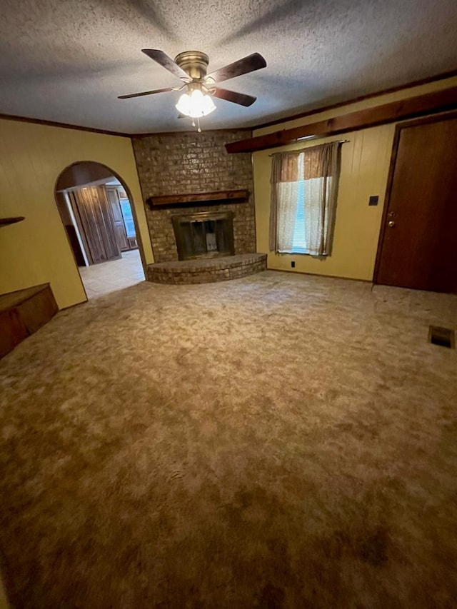 unfurnished living room with a brick fireplace, a textured ceiling, ceiling fan, and light carpet