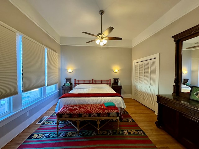 bedroom with wood-type flooring, a closet, ceiling fan, and crown molding