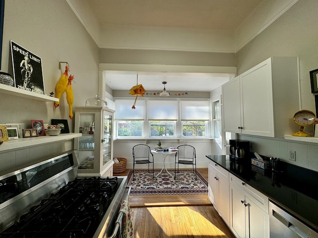 kitchen with crown molding, white cabinets, light hardwood / wood-style floors, and appliances with stainless steel finishes