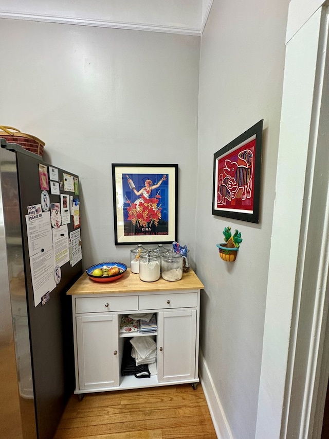 interior space with stainless steel fridge, white cabinetry, and light hardwood / wood-style flooring