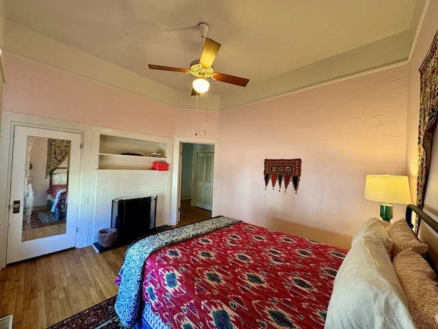 bedroom featuring ceiling fan, dark hardwood / wood-style floors, and a brick fireplace