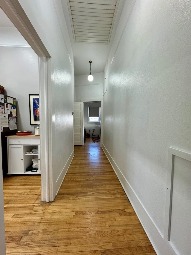 hallway with light hardwood / wood-style flooring and crown molding