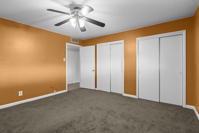 unfurnished bedroom with two closets, baseboards, visible vents, and carpet floors
