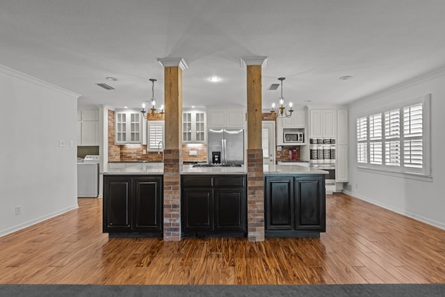 kitchen with an inviting chandelier, washer / dryer, appliances with stainless steel finishes, and white cabinetry