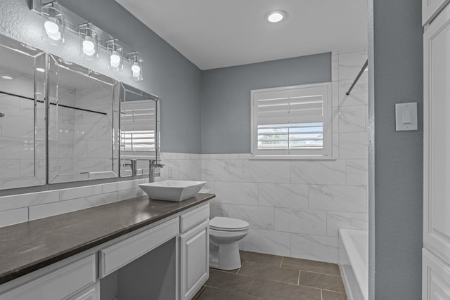 bathroom featuring vanity, toilet, tile patterned floors, a wainscoted wall, and tile walls