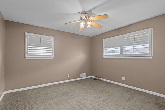 carpeted spare room with ceiling fan, visible vents, and baseboards