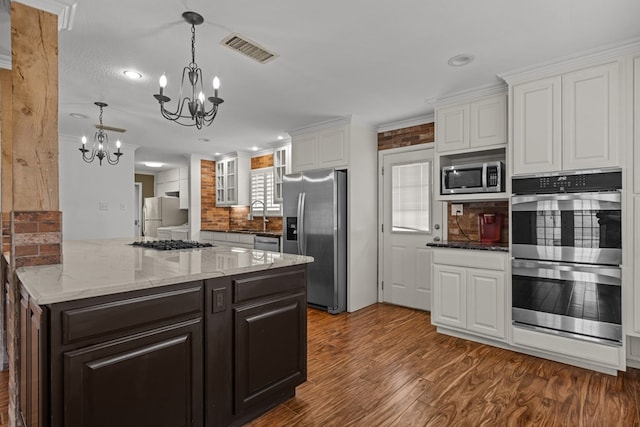 kitchen featuring backsplash, visible vents, a chandelier, stainless steel appliances, and white cabinetry