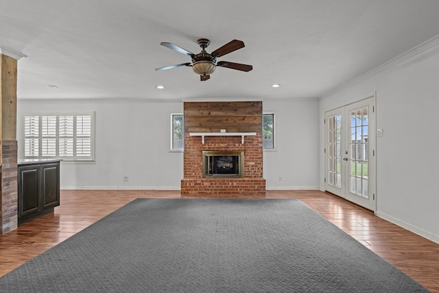 unfurnished living room with baseboards, a ceiling fan, wood finished floors, and a healthy amount of sunlight