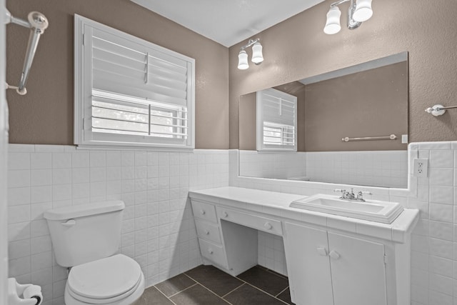 bathroom with toilet, tile walls, tile patterned flooring, and a wainscoted wall