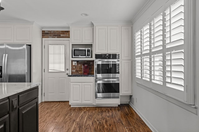 kitchen with crown molding, light stone counters, stainless steel appliances, white cabinetry, and dark wood-type flooring