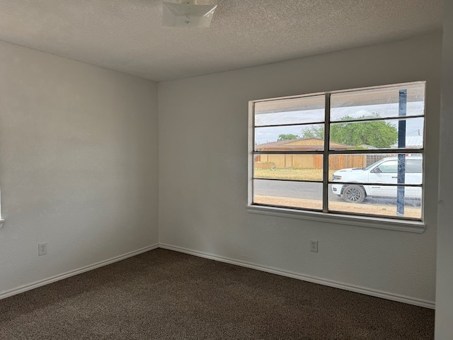 unfurnished room featuring dark colored carpet, baseboards, and a textured ceiling