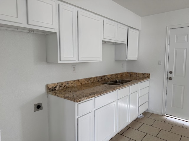 kitchen with white cabinetry, stone countertops, a sink, and light tile patterned floors