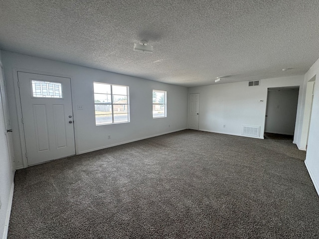 foyer with carpet floors, a textured ceiling, and baseboards