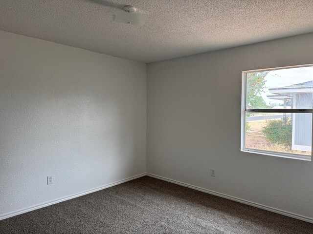 carpeted empty room featuring baseboards and a textured ceiling