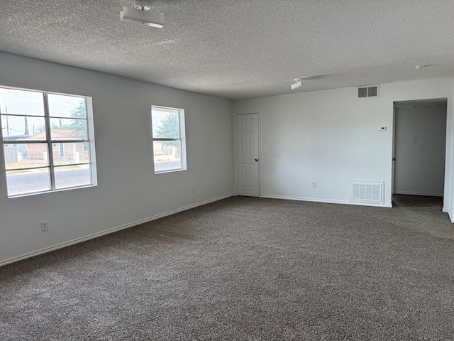 empty room with dark colored carpet, a textured ceiling, and baseboards