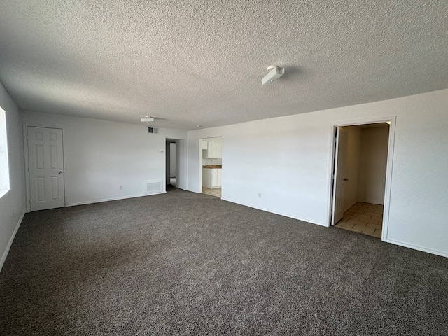 empty room featuring carpet flooring, a textured ceiling, and baseboards