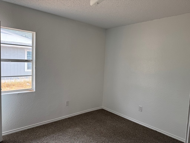 unfurnished room with dark colored carpet and baseboards