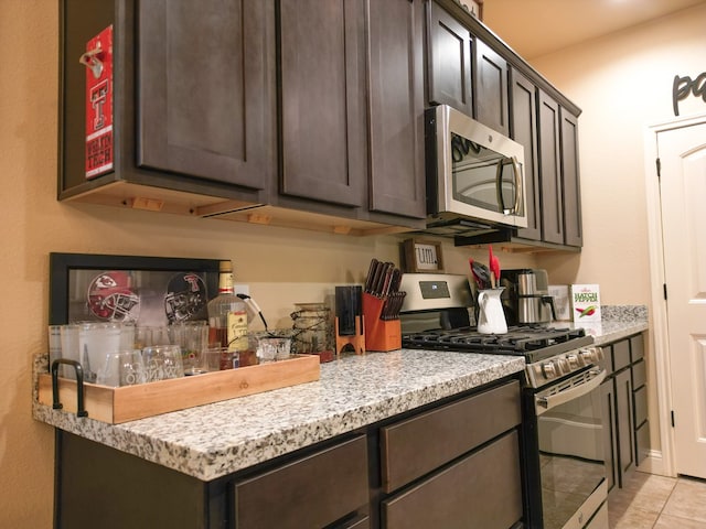 32 Balmoral Cir, Odessa, TX 79765 - kitchen with appliances with stainless steel finishes, dark brown cabinets, light tile patterned flooring, and light stone countertops