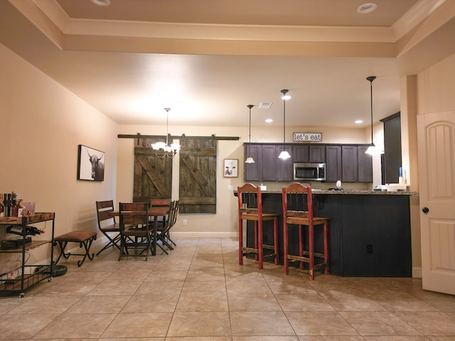 32 Balmoral Cir, Odessa, TX 79765 - kitchen with a barn door, stainless steel microwave, light stone countertops, a tray ceiling, and light tile patterned floors