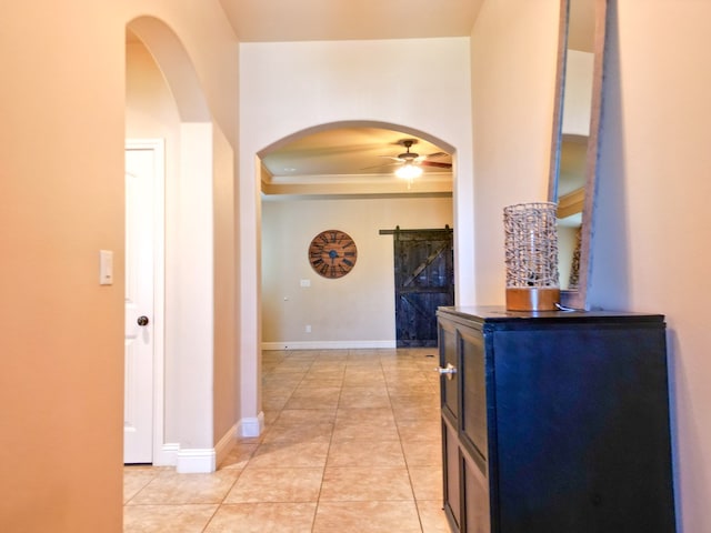 32 Balmoral Cir, Odessa, TX 79765 - hallway featuring arched walkways, a barn door, a tray ceiling, crown molding, and light tile patterned floors