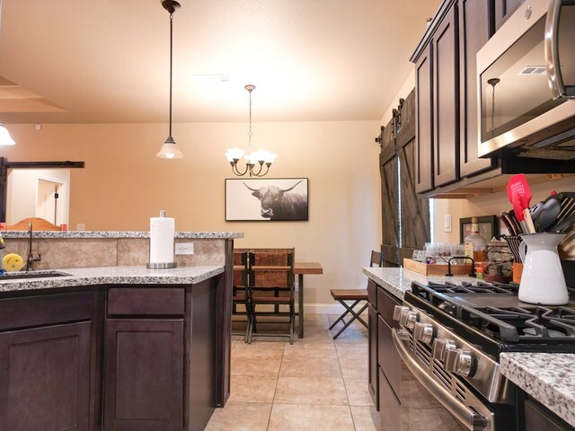 32 Balmoral Cir, Odessa, TX 79765 - kitchen featuring appliances with stainless steel finishes, dark brown cabinets, a barn door, pendant lighting, and light tile patterned floors