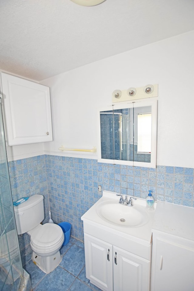 bathroom featuring walk in shower, vanity, tile walls, tile patterned flooring, and toilet