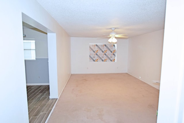 spare room featuring a textured ceiling, carpet floors, and ceiling fan