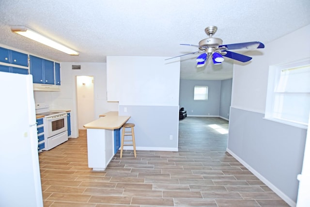 kitchen with blue cabinetry, light hardwood / wood-style flooring, range hood, a textured ceiling, and white appliances