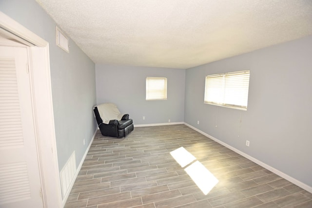 unfurnished room featuring a textured ceiling and light hardwood / wood-style flooring