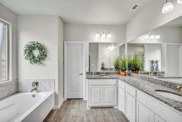 8430 E County Rd 114, Midland, TX 79706 - full bath with double vanity, a garden tub, and wood finished floors