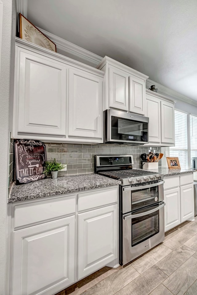 8430 E County Rd 114, Midland, TX 79706 - kitchen with stainless steel appliances, tasteful backsplash, white cabinetry, crown molding, and light stone countertops