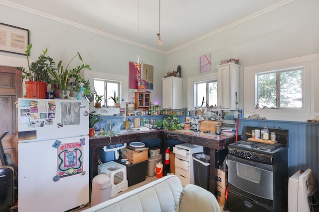106 SE 4th St, Marathon, TX 79842 - kitchen featuring freestanding refrigerator, plenty of natural light, ornamental molding, white cabinets, and gas stove