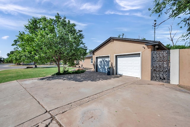 1600 W Kansas Ave, Midland, TX 79701 - view of side of home with stucco siding, driveway, a garage, and a lawn