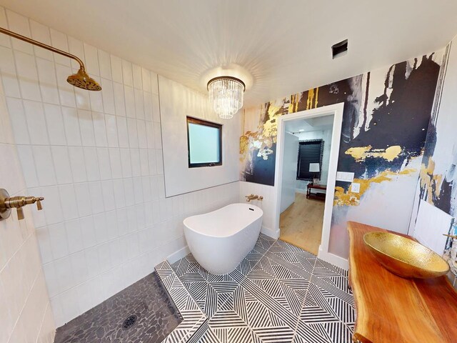1411 NE Mustang Dr, Andrews, TX 79714 - full bath with a tile shower, a freestanding bath, a chandelier, vanity, and tile walls