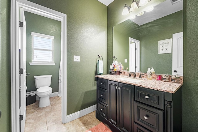 bathroom with vanity, baseboards, a textured wall, and toilet