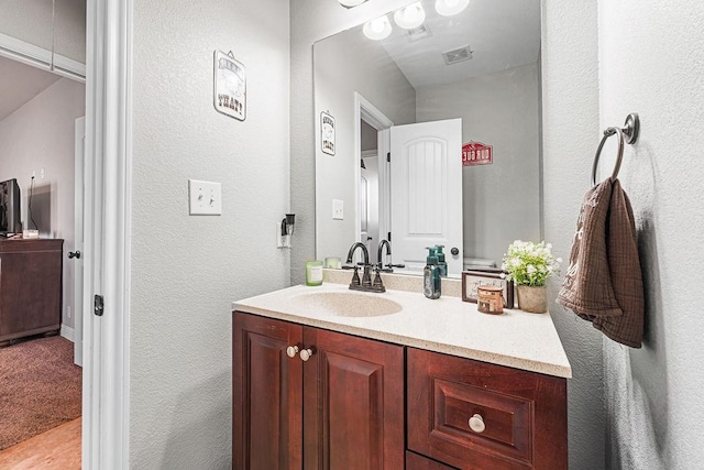 bathroom with vanity, a textured wall, and visible vents
