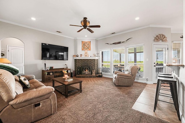 tiled living area featuring crown molding, arched walkways, a ceiling fan, and visible vents