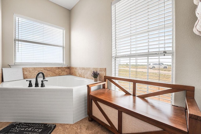 full bath featuring a textured wall, a bath, and a wealth of natural light