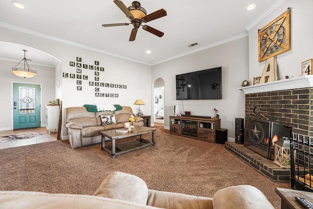 carpeted living area with crown molding, arched walkways, a ceiling fan, baseboards, and visible vents