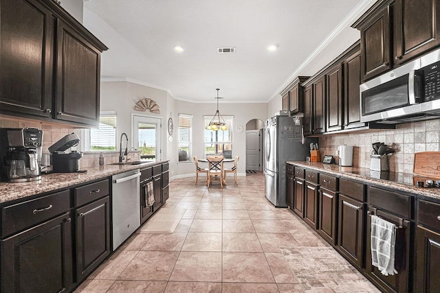 kitchen with visible vents, light stone countertops, tasteful backsplash, a sink, and appliances with stainless steel finishes