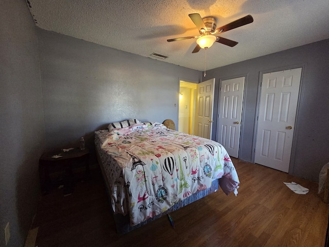 3301 N Jackson Ave, Odessa, TX 79762 - bedroom with wood finished floors, a textured ceiling, a ceiling fan, and two closets