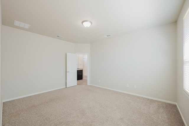 empty room with light colored carpet, visible vents, and baseboards