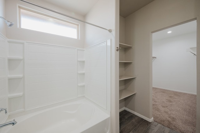 full bathroom featuring baseboards, a walk in closet, and washtub / shower combination