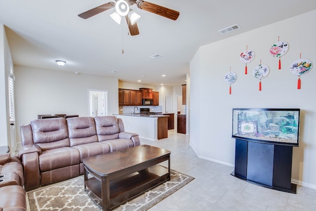living area featuring light tile patterned floors, baseboards, ceiling fan, and visible vents